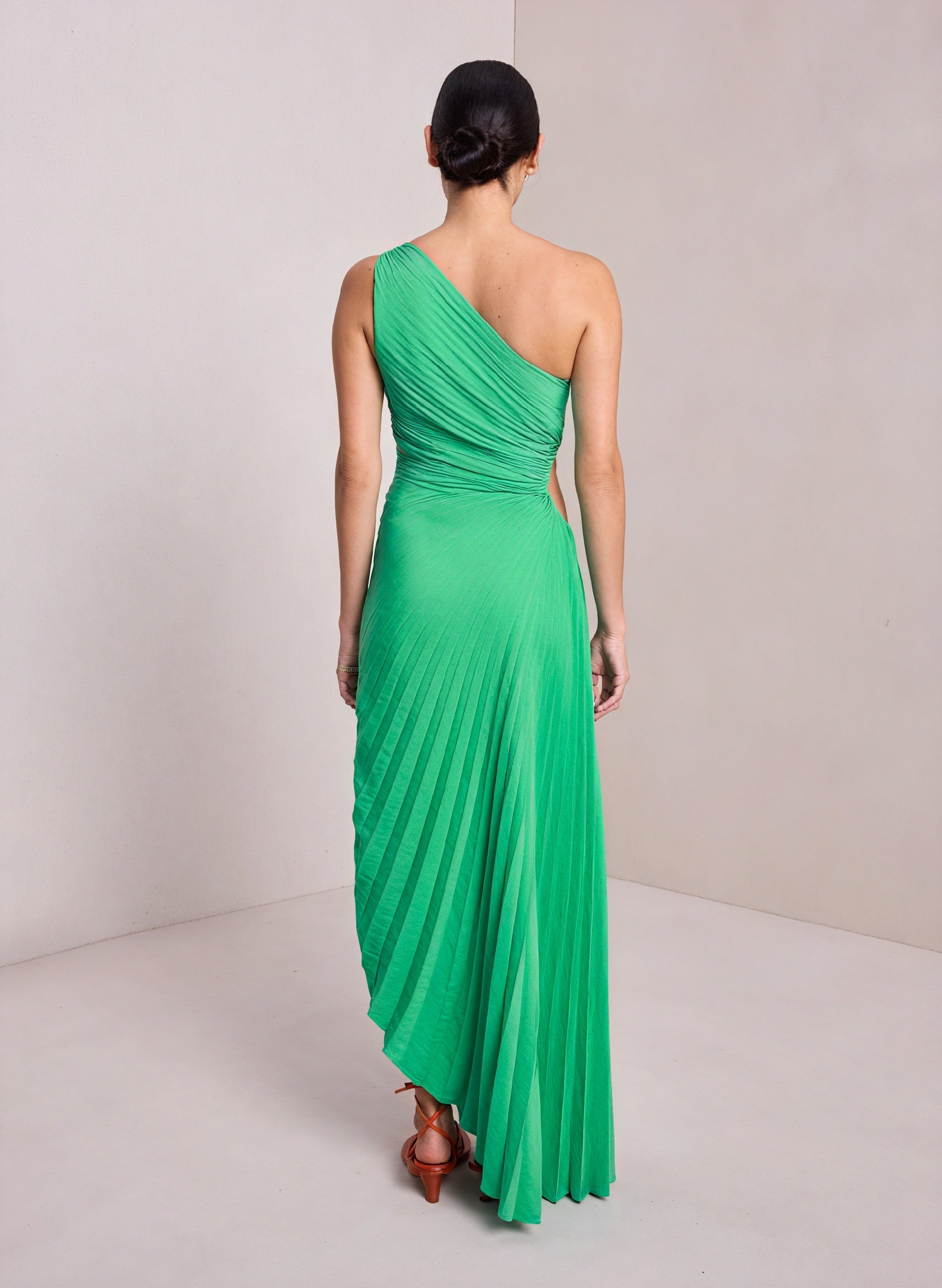 Light beige monospalla pleated dress with asymmetric hem by Montaracrest, featuring a single shoulder strap and flowing fabric.