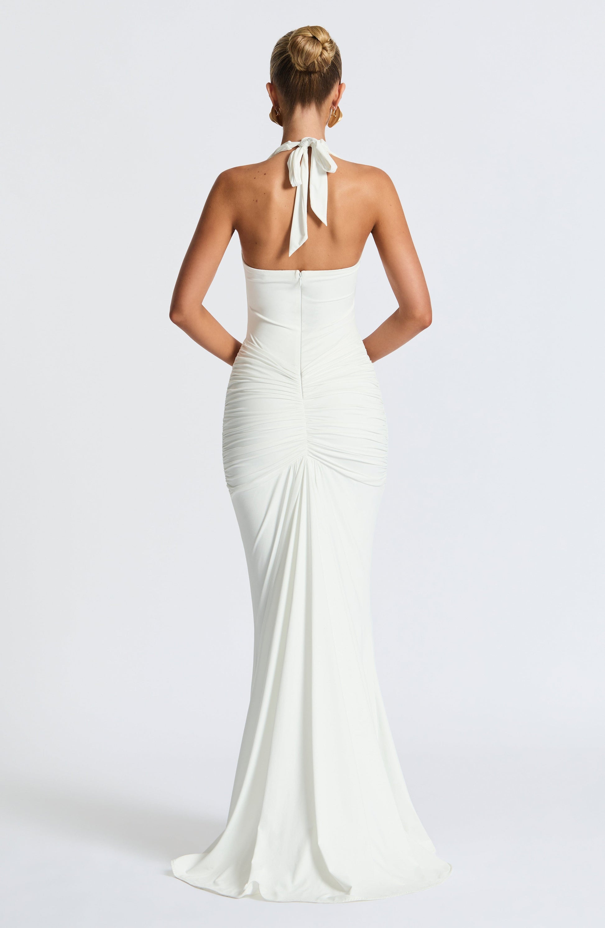 White Freja halterneck dress by Montaracrest, featuring a flowing maxi style with elegant rosetta details, perfect for summer occasions.